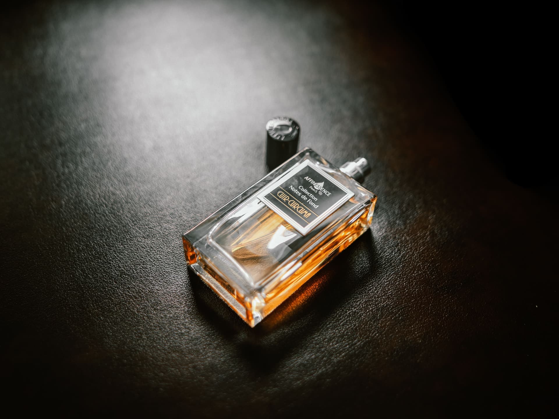 Amber-glass fragrance bottles lit low against a dark, smoky background